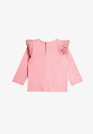 Różowa bawełniana bluzka z długim rękawem, z koronkowymi falbanami na rękawach, okrągłym dekoltem i pięcioma guzikami z tyłu. Gładka faktura, prosty design.
