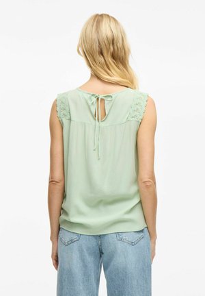 Mint green sleeveless top with lace accents on shoulders, keyhole back detail, and a tie closure. Smooth texture, relaxed fit.