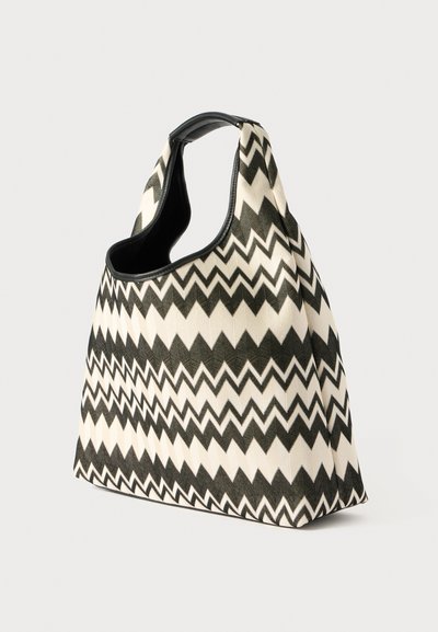 Black and white zigzag patterned tote bag with a soft fabric body and a smooth black leather trim, featuring a wide shoulder strap design.