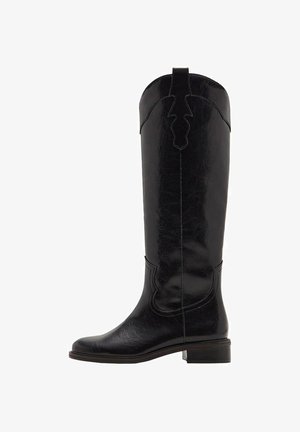 Botte noire en cuir jusqu'au genou avec une finition texturée, présentant un design découpé en haut et un petit talon empilé. Surface lisse avec des coutures décoratives.