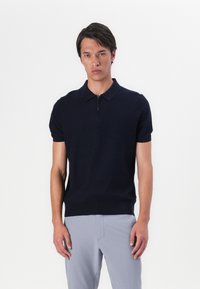 Marineblå kortermet polo skjorte med halv-zip krage. Laget av glatt stoff, tettsittende design, og med ribbestrikket kant for et strukturert utseende.