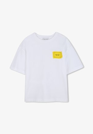 T-shirt blanc à manches courtes présentant un patch carré jaune avec un contour noir, mettant en avant un motif cousu. Tissu en coton doux.