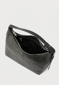 Geantă neagră din piele cu închidere cu fermoar și o curea scurtă. Textură netedă, formă înclinată și un buzunar interior mic vizibil.