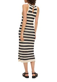 Robe tricotée rayée en noir et crème, sans manches, avec un détail de dos en keyhole et une fente sur le côté à l'ourlet.