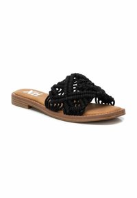 Sandalia deslizante tejida negra con un upper decorativo de estilo macramé y suela marrón claro, que cuenta con un tacón plano y textura suave.