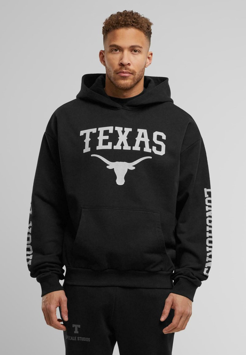 Crna hoodie s kapuljačom na kojoj piše "TEXAS" i grafikom dugog roga u bijeloj boji. Ima prednji džep te rebraste manžete i rub.