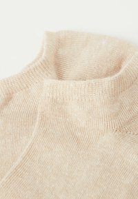 Suéter de cuello alto en beige claro con textura acanalada, material suave y un cuello relajado y holgado.