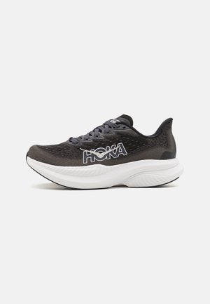 Chaussure de course Hoka noire et grise avec une semelle blanche épaisse et un grand logo HOKA sur le côté, vue de la face latérale externe.