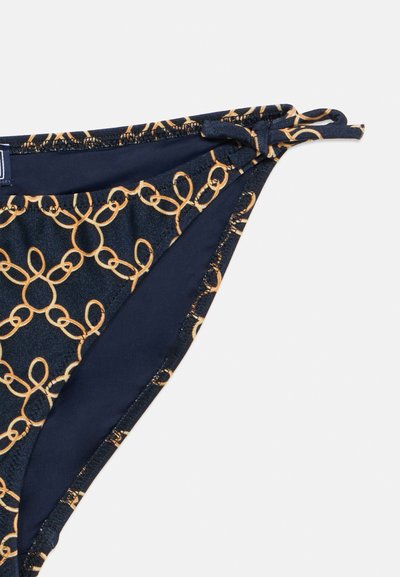 Σκούρο μπλε μαγιό σλιπ με σχέδιο από χρυσούς κρίκους, με ελαστικές πλευρές και λεία υφή. Ρυθμιζόμενοι δεσμοί για προσαρμοσμένη εφαρμογή.