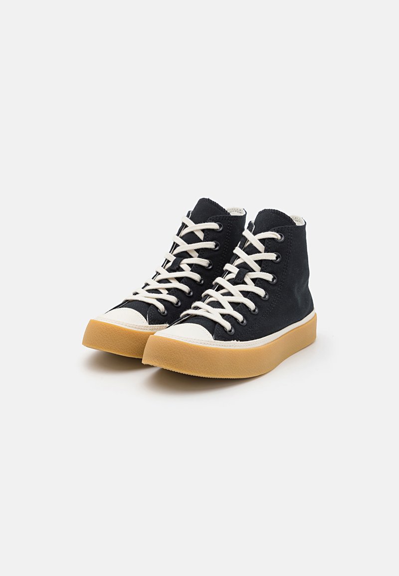 Zapatillas altas de lona negra con acentos y cordones blancos. Cuentan con una gruesa suela de goma y un upper texturizado con detalles cosidos.