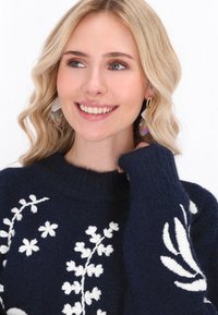 Navy gestrickter Pullover mit weißer Blumenstickerei, Rundhalsausschnitt und strukturiertem Stoff. Enthält goldene und schillernde Ohrhänger.