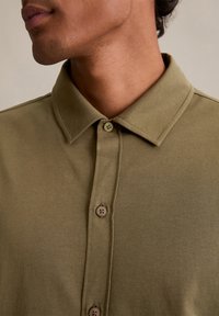 Korte mouwen, olijfgroene polo met een knoopsluiting, met contrasterende bruine knopen en een zachte, geztructureerde stof.