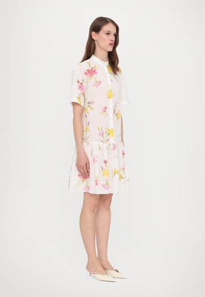 White floral dress with short sleeves, featuring pink and yellow flower patterns and a flared hemline. Smooth fabric texture.