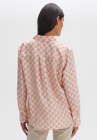 Long-sleeve, lightweight shirt in a cream color with a red and beige grid pattern; features a collar and buttoned cuffs.