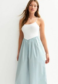 White sleeveless top paired with a light blue vertical striped wide-leg skirt, featuring an elastic waistband and flowing fabric.
