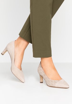 Beige højhælede pumps med spids tå, der har glatte og teksturerede mønstre, små blokhæle og et tofarvet design.