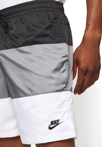 Shorts i lätt material i svart, grått och vitt; har en elastisk midja och en liten svart Nike-logotyp.