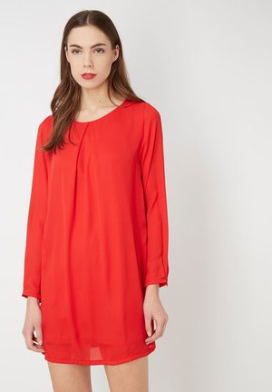 Vestido rojo de manga larga con escote redondo. Hecho de una tela ligera, presenta un corte holgado y sutiles pliegues cerca del escote.
