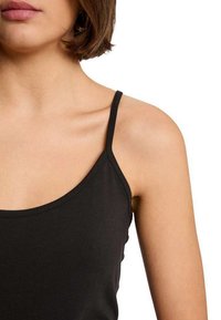 Top camisolé noir ajusté avec des bretelles fines, un décolleté arrondi et une texture lisse et extensible. Pas de motifs visibles ni d'embellissements.
