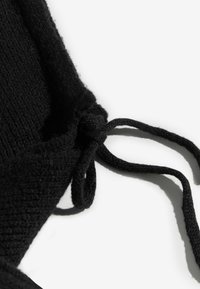 Fekete kötött anyag texturált felülettel, az élekhez állítható megkötőkkel. Puha, hajlékony anyag egyszerű dizájnnal.