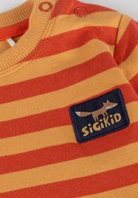 Langärmliges Baumwollhemd mit orange und gelben horizontalen Streifen. Beinhaltet einen blauen Patch mit einem Fuchs-Design und dem "Sigikid"-Logo.