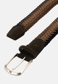 Flätad bälte med brun och svart texturerad tyg, accentuerad av mörka mockaändar och en spänne i silverfärg. Hållbar och flexibel design.
