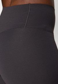 Magas derekú fekete leggings sima, rugalmas anyagból, laposvarrásos részletekkel, kényelmes, varrás nélküli derékkal.