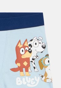 Svjetloplavi dječji šorts s likovima crtanih pasa: smeđi pas s dijamantom, crno-bijeli šareni pas i pas s naočalama.