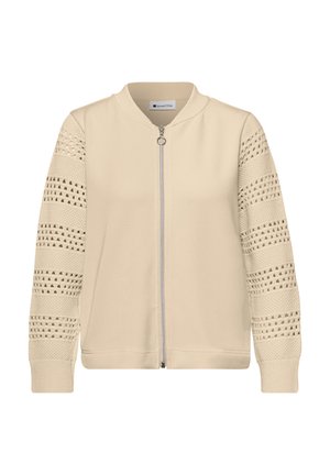 Beżowa kurtka na zamek z dzianinowymi rękawami o fakturze z wzorem ażurowym oraz ściągaczami na mankietach i kołnierzu.