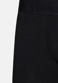 Schwarze Boxershorts aus einem weichen Stoff verfügen über einen dicken Bund mit eingeprägtem Text. Das Design beinhaltet flache Nähte für zusätzlichen Komfort.