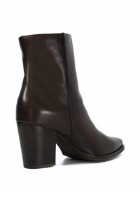 Bruine leren enkellaars met een spitse teen, een gladde textuur, een rits aan de zijkant en een gestapelde hak met horizontale groeven.