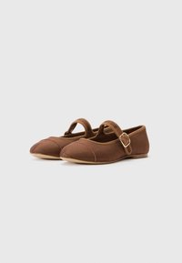 Brown fabric Mary Jane shoes with a rounded toe, textured surface, and a small buckle strap. Flat sole with subtle stitching details.