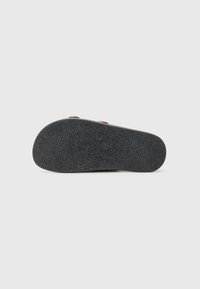 Sort gummisul med tekstureret grebmønster, udstyret med to bronzefarvede nitter. Flad design med afrundede kanter.