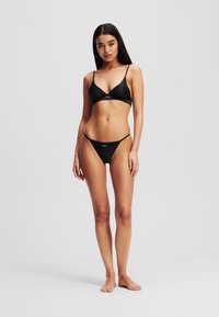 Zwart bikini set met een driehoekige bralette met dunne bandjes en een bijpassende low-rise onderkant. Gladde stof met minimale branding.