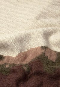 Soft knitted fabric with cream, pink, olive green, and brown color blocks and a slightly fuzzy texture.