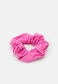 Rožaina teksturēta scrunchie, kas izgatavota no mīkstas auduma, ar savilktu dizainu un apaļu formu, kurai ir pleatētas detaļas.