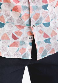 Koszula z krótkim rękawem z lekkiego materiału, z wielokolorowym geometrycznym wzorem w różowe, niebieskie i białe trójkąty.