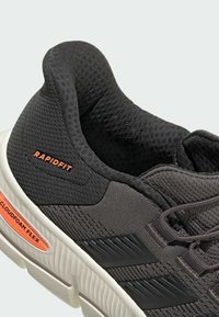 Black athletic shoe with mesh upper, textured accents, and white sole. Features orange branding and cushioned Cloudfoam Flex technology.