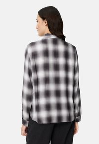 Schwarz-weiß kariertes Hemd mit langen Ärmeln, weichem Stoff und abgerundetem Saum. Verfügt über einen klassischen Kragen und geknöpfte Manschetten.