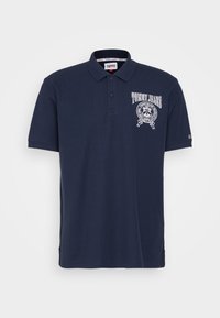 Námorně modré polo triko vyrobené z bavlny. Obsahuje límeček, tři knoflíky a logo na levé části hrudi. Krátké rukávy s jemným žebrováním.