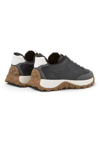 Sneaker casual con tomaia in pelle nera, dettagli in camoscio grigio, linguetta bianca sul tallone e suola in gomma marrone testurizzata.