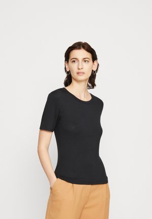 Black short-sleeve T-shirt made of soft fabric, featuring a round neckline and a fitted design. Paired with light-colored trousers.