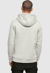 Világosszürke, kapucnis pulóver, puha anyagból készült, kenguruzsebbekkel és bordázott mandzsettákkal, valamint aljjal rendelkezik. Egyszerű, díszítetlen dizájn.