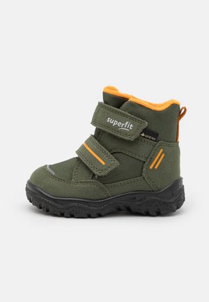 Zielono-pomarańczowy zimowy but dziecięcy z czarną podeszwą, dwoma paskami na rzep i materiałem Gore-Tex zapewniającym wodoodporność i ciepło.