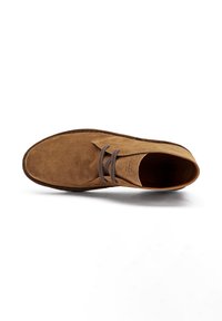 Zapato de ante marrón con punta redonda y diseño de cordones, visto desde arriba sobre un fondo blanco.
