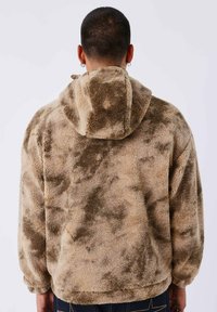 Felpa con cappuccio marrone e beige in pile, con una superficie morbida e texture. Presenta un cappuccio e una vestibilità ampia, con un sottile motivo marmorizzato su tutta la superficie.