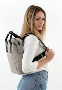 Grauer wasserdichter Rucksack mit schwarzen Riemen und Beschlägen. Verfügt über einen Rollverschluss an der Oberseite und eine frontale Klappentasche. Kompakte und stromlinienförmige Gestaltung.