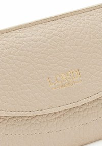 Beige leren portemonnee met een gestructureerd oppervlak, voorzien van een in goud gedrukt logo, een ronde klep en gestikte details langs de randen.
