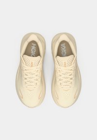 Béžové běžecké boty s prodyšnou tkaninovou svrchní částí, texturovaným panelem se šňůrkami, reflexními detaily a polstrovanou stélkou. Logo viditelné na jazyku.