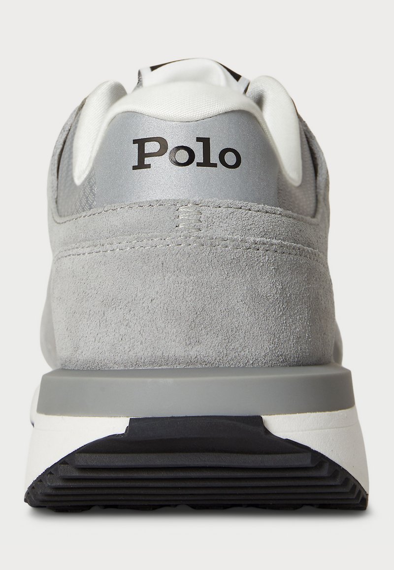 Graue Wildledersneaker mit einem gepolsterten weißen Kragen, silbernen Akzenten und einem schwarzen "Polo"-Logo an der Ferse. Strukturiertes Außensohlenprofil für besseren Halt.